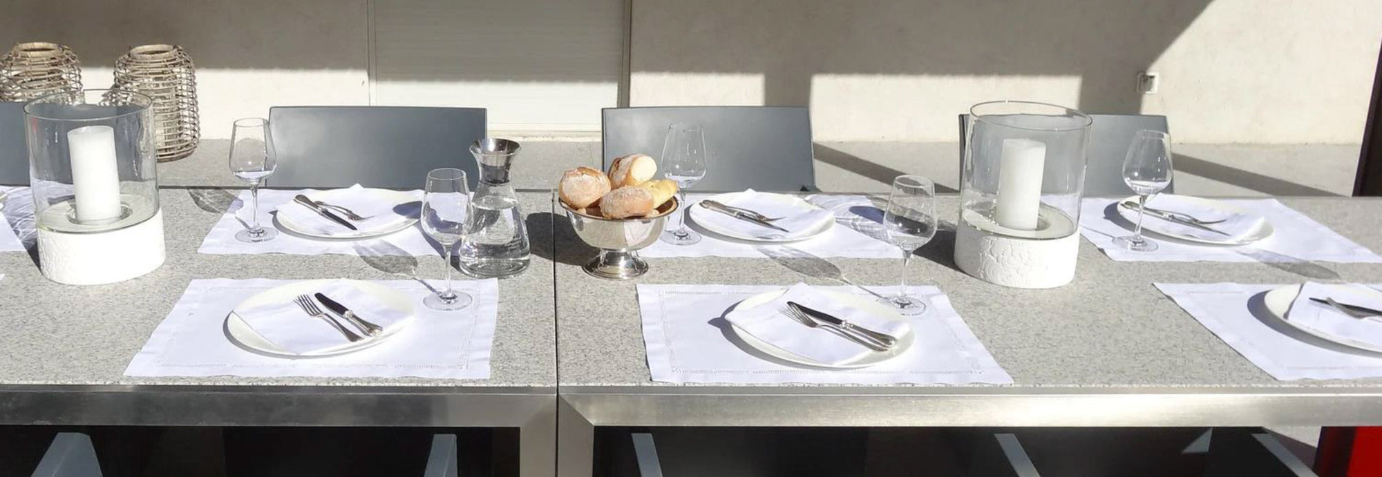 Elegante Tischdekoration mit Stoffservietten, Gläsern und Besteck auf einem modernen Esstisch.