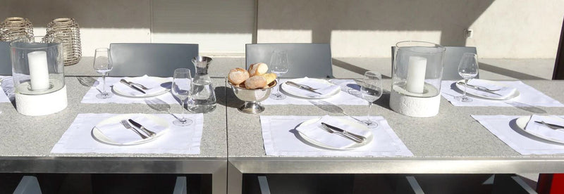 Elegante Tischdekoration mit Stoffservietten, Gläsern und Besteck auf einem modernen Esstisch.