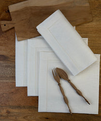 Stoffservietten Gent 60x60cm handgestickt mit Hohlsaum auf Holztisch.