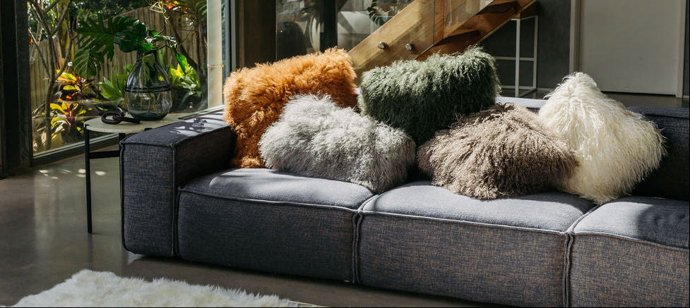 Lammfellkissen in verschiedenen Farben auf einem Sofa dekoriert