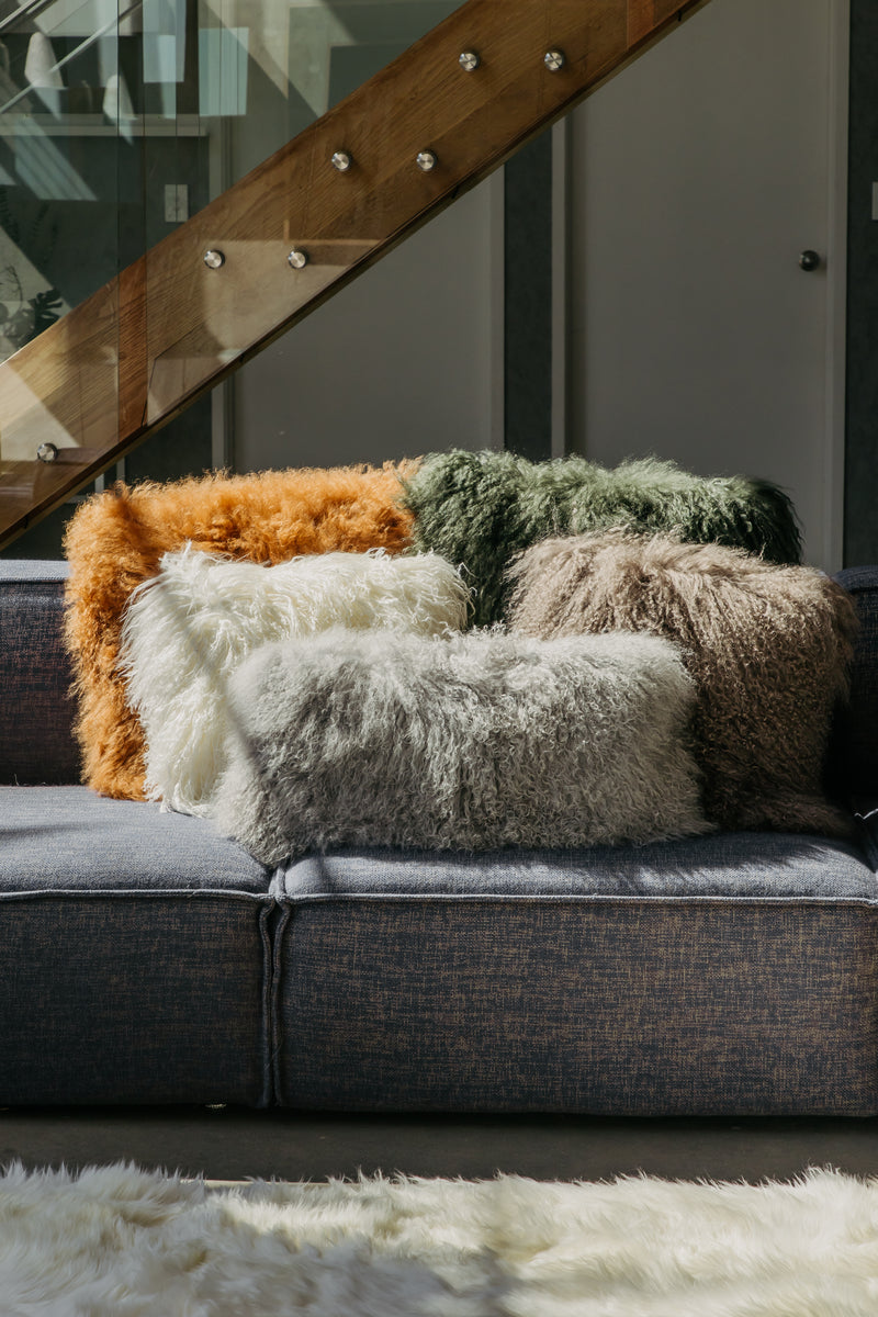 Lammfell Kissen in verschiedenen Farben auf einem Sofa dekoriert