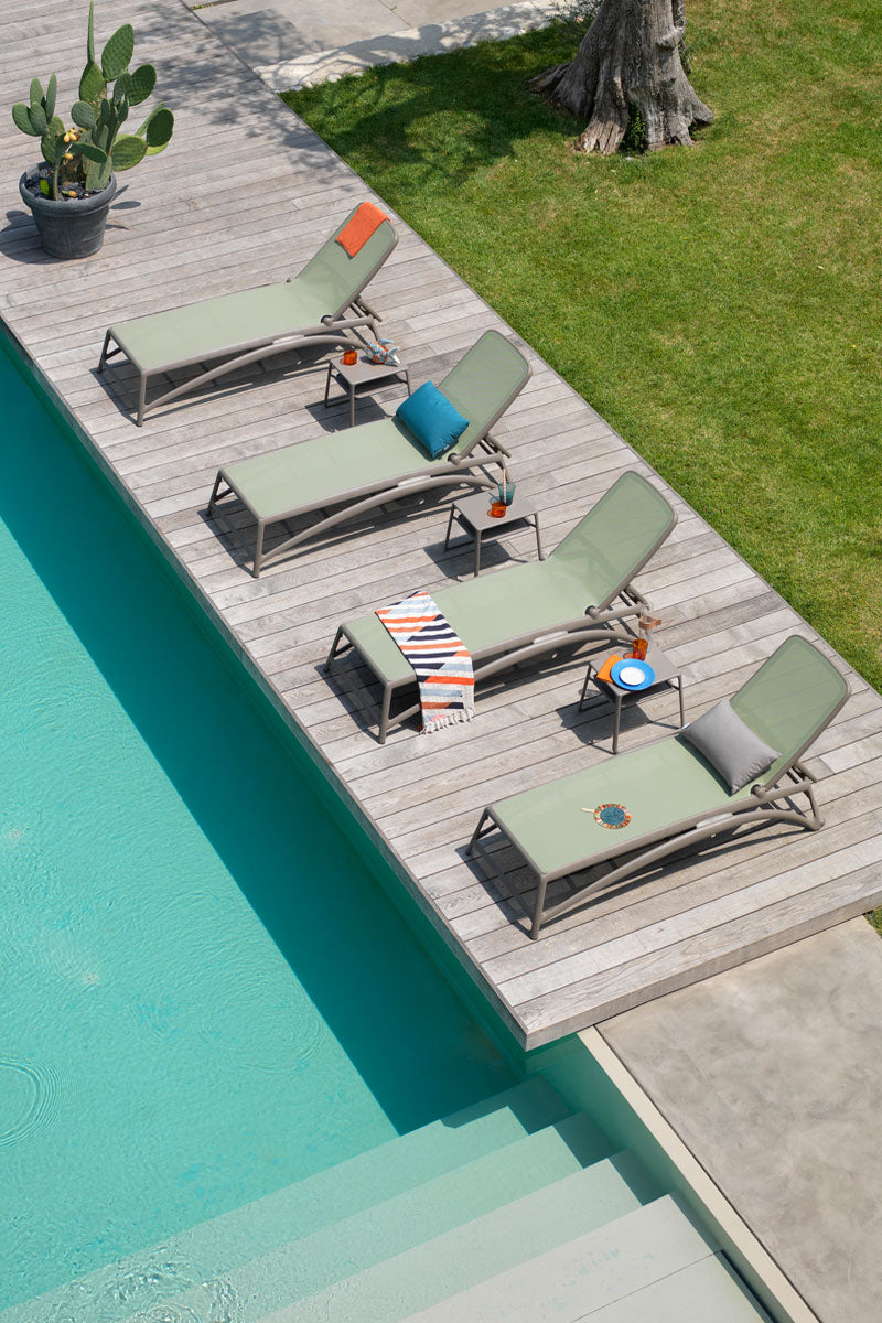 Vier Sonnenliegen Agarve-gruen am Pool auf Holzboden