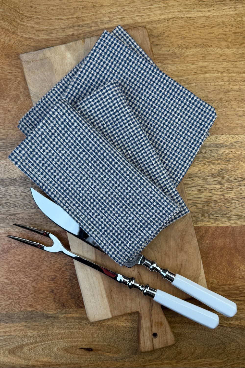 Stoffserviette Bistro 40x40cm auf Holzbrett mit Tranchierbesteck dekoriert.