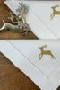 Stoffservietten Christmas Deer 50x50cm in Gold handgestickt mit Hohlsaum auf Holztisch dekoriert.