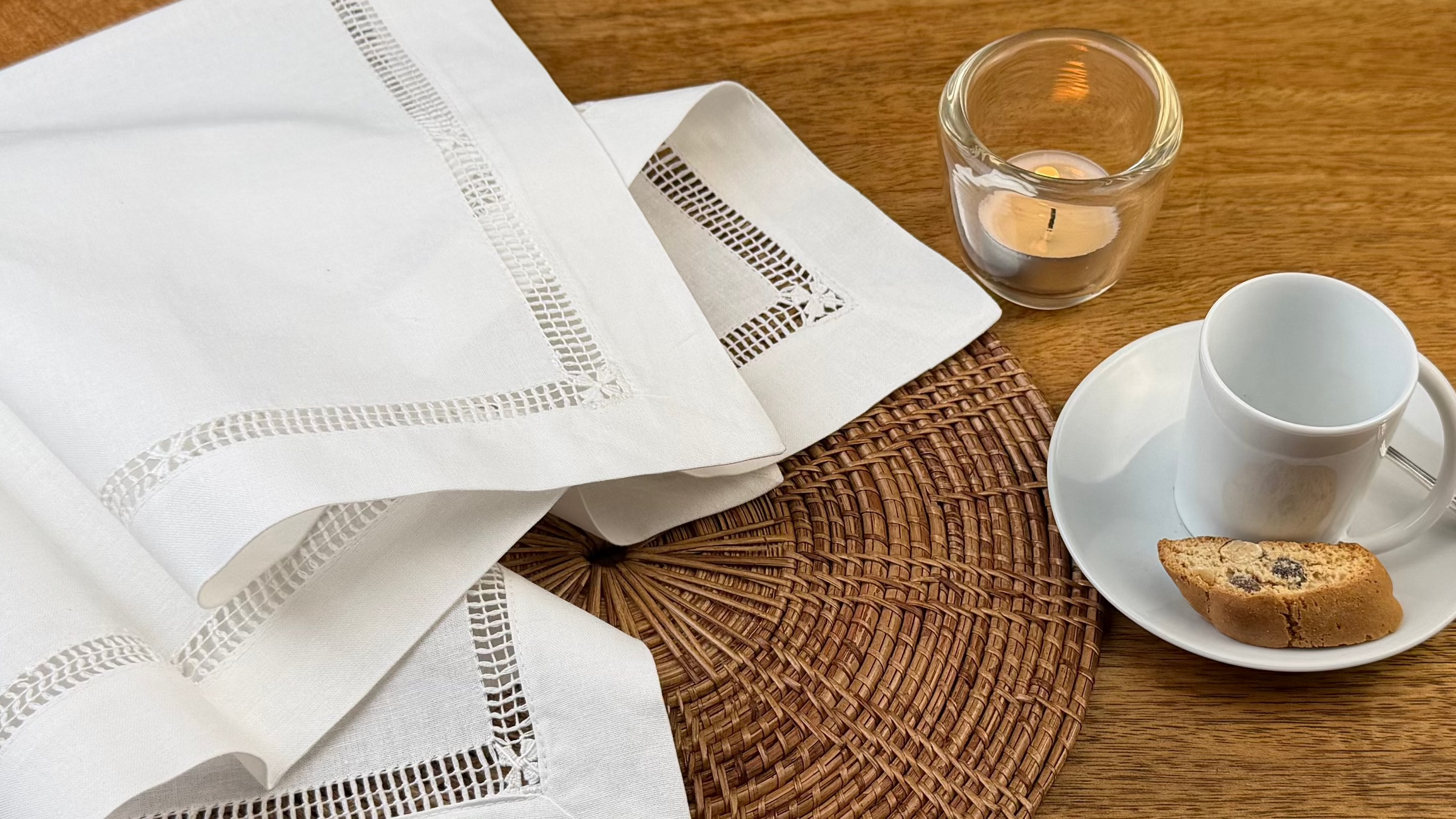 Stoffserviette weiß Fiorenze mit Kaffeetasse und Teelicht dekoriert.