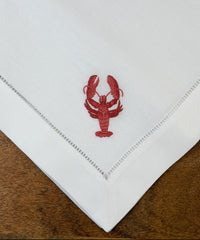 Nahaufnahme der Stoffservietten Hummer 50x50cm handgestickt mit Hohlsaum auf Holztisch 