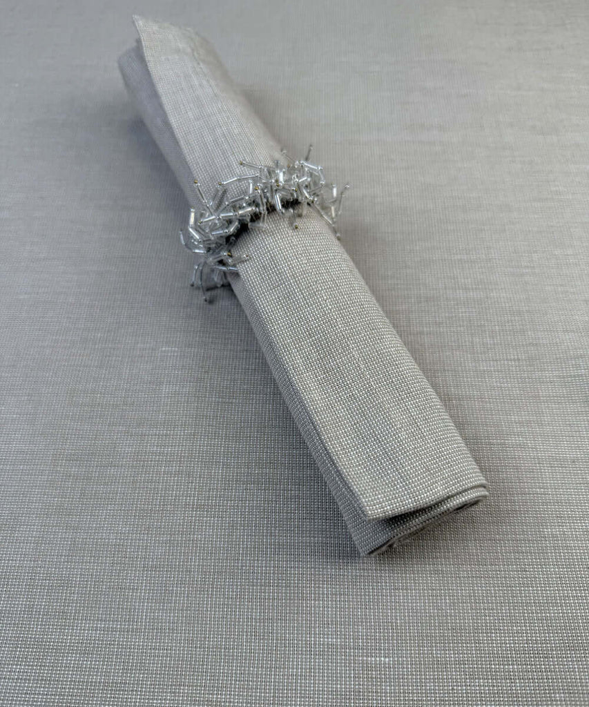 Stoffserviette Keitum 50x50cm Farbe Sand mit Serviettenring aus weißen Glasperlen.