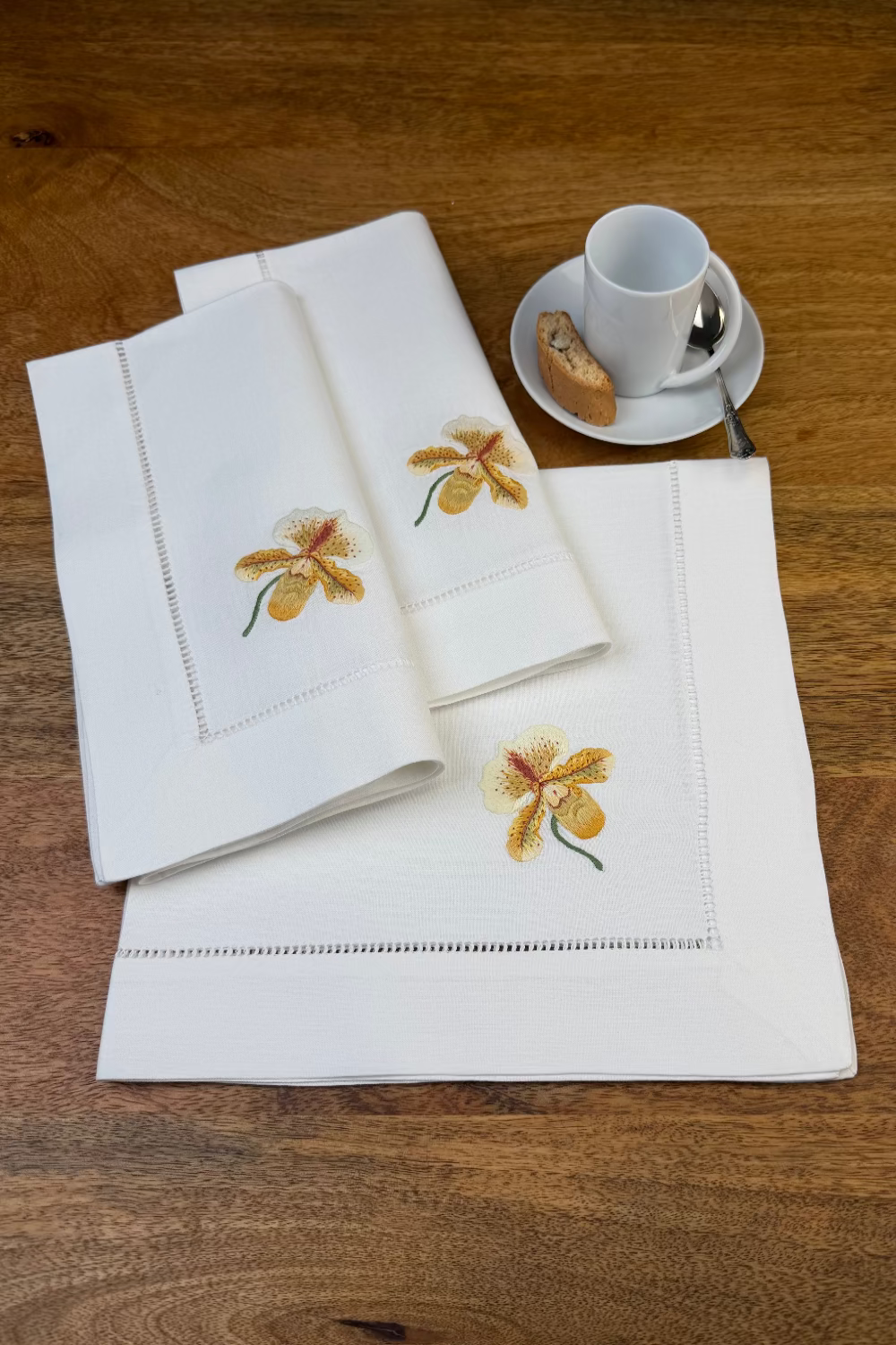 Stoffservietten Orchideen 50x50cm handgestickt mit Hohlsaum auf Holztisch zum Kaffee gedeckt.