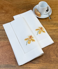 Stoffservietten Orchideen 50x50cm handgestickt mit Hohlsaum auf Holztisch zum Kaffee gedeckt.