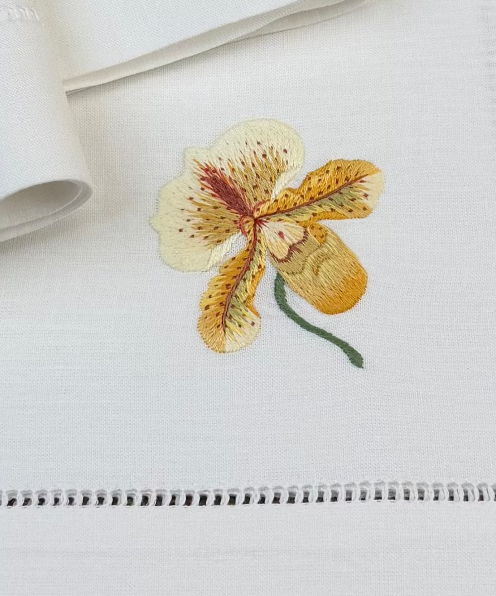Nahaufnahme des gestickten Motivs derStoffservietten Orchideen 50x50cm handgestickt mit Hohlsaum.