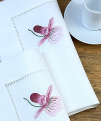 Stoffservietten Orchidee Rosa 50x50cm handgestickt mit Hohlsaum auf Holztisch mit Kaffeetass eingedeckt.