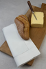 Stoffserviette Sylt 50x50cm Hohlsaum mit 4cm Bordüre auf Holzbrett mit Baguette und Butter.