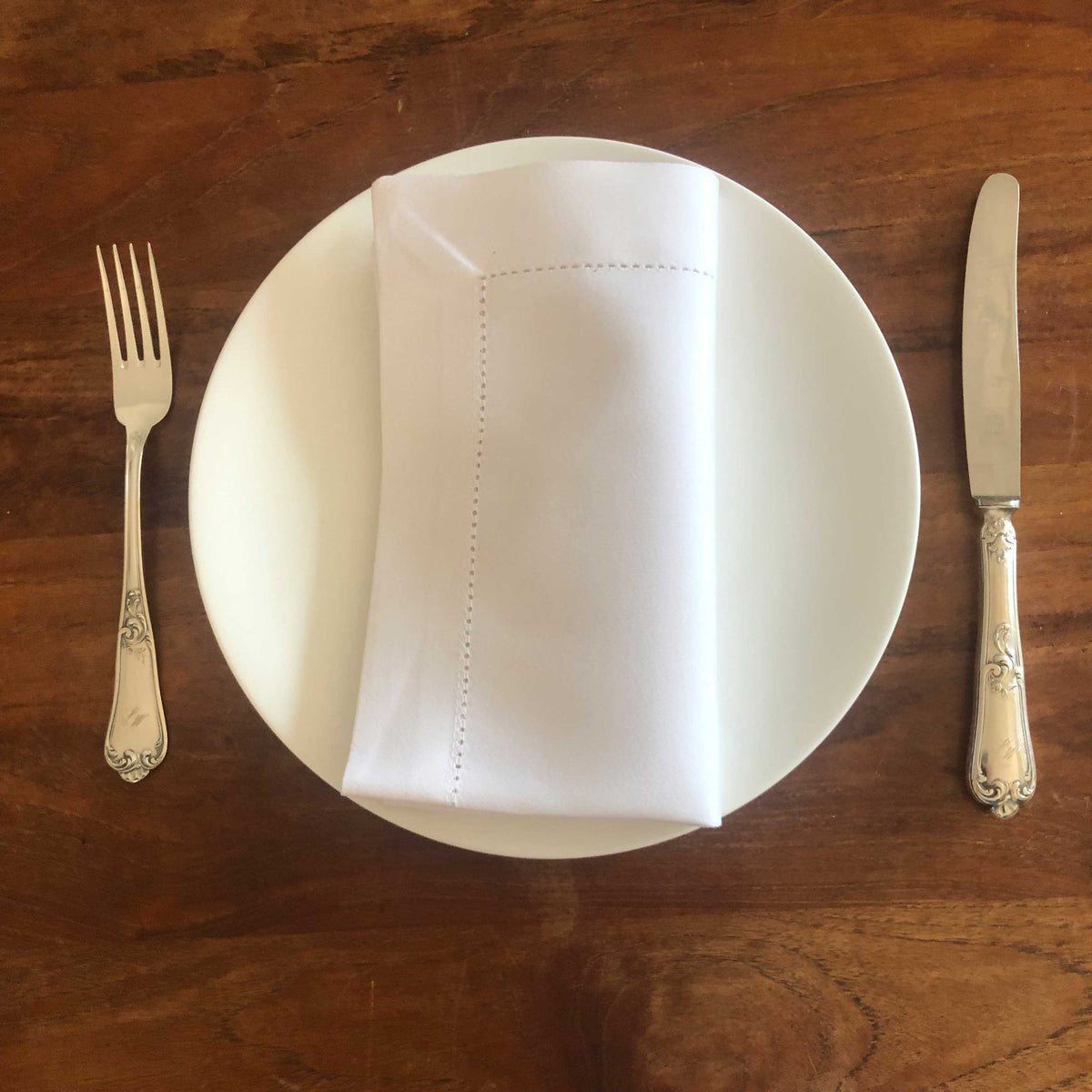 Stoffservietten 45x45cm auf einem weißen Teller mit Besteck, elegant gedeckte Tafel.