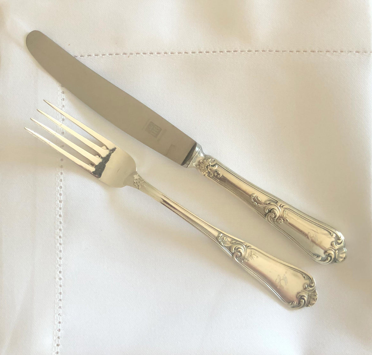 Silberbesteck auf weißer Stoffserviette, elegant und rustikal, perfekt für festliche Anlässe.