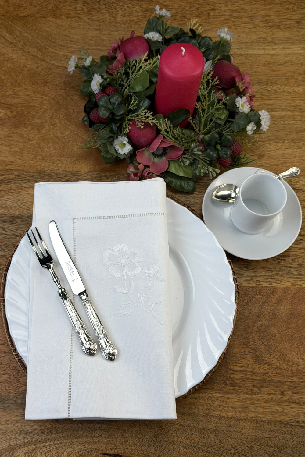 Stoffservietten Weiße Rose50x50cm handgestickt mit Hohlsaum, dekoriert mit Blumenarrangement, Kaffeeservice und Kuchen Besteck auf Holztisch.