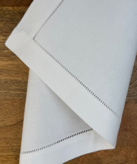 Stoffserviette weiss Toscana auf Holztisch drapiert.