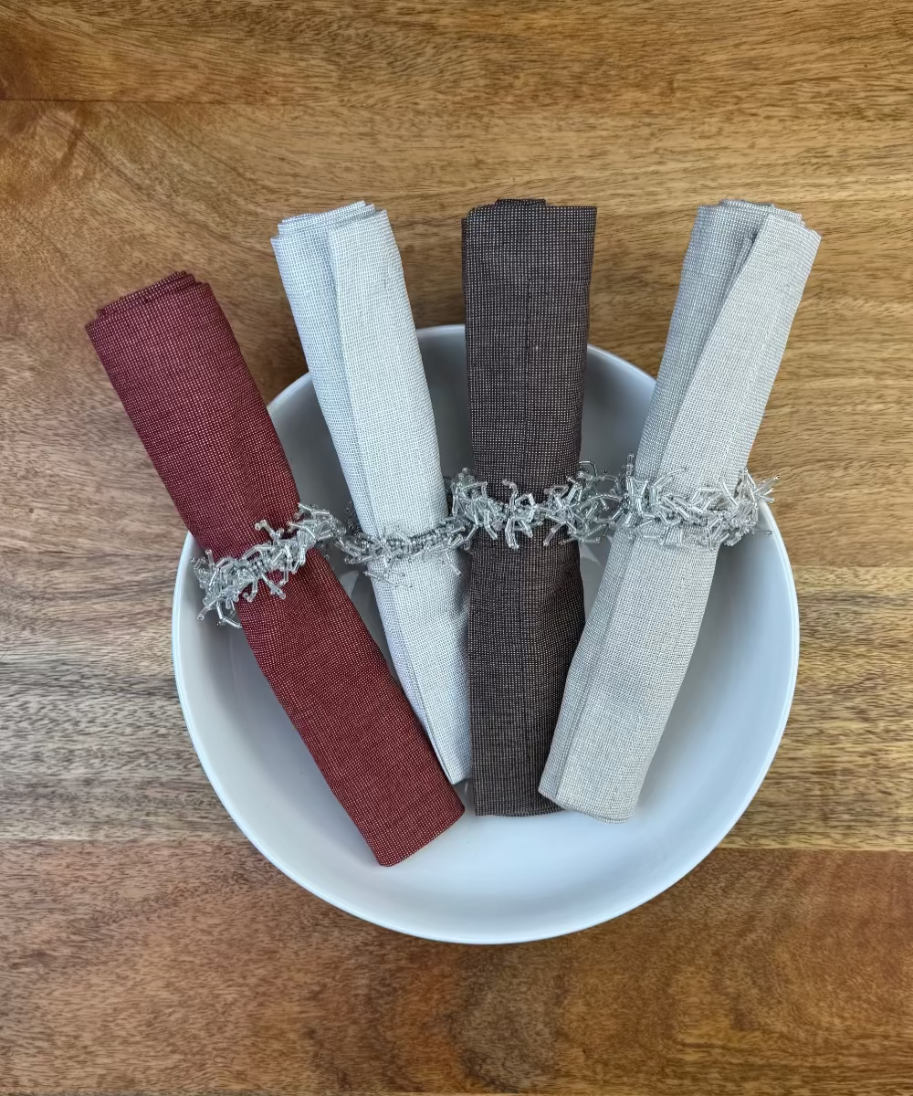 Stoffservietten Keitum alle 4 Farben in der Größe 50x50cm mit Serviettenringen in einer Porzellan Schüssel arrangiert.