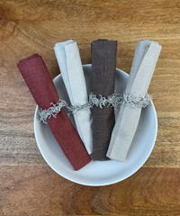 Stoffservietten Keitum alle 4 Farben in der Größe 50x50cm mit Serviettenringen in einer Porzellan Schüssel arrangiert.