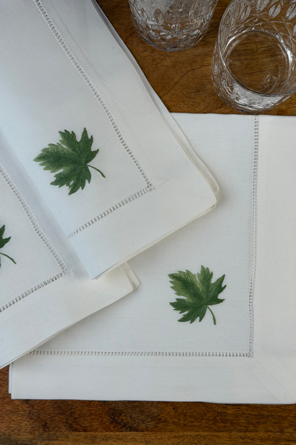 Stoffservietten Ahorn 50x50cm handbestickt und mit Gläsern auf Holztisch dekoriert.