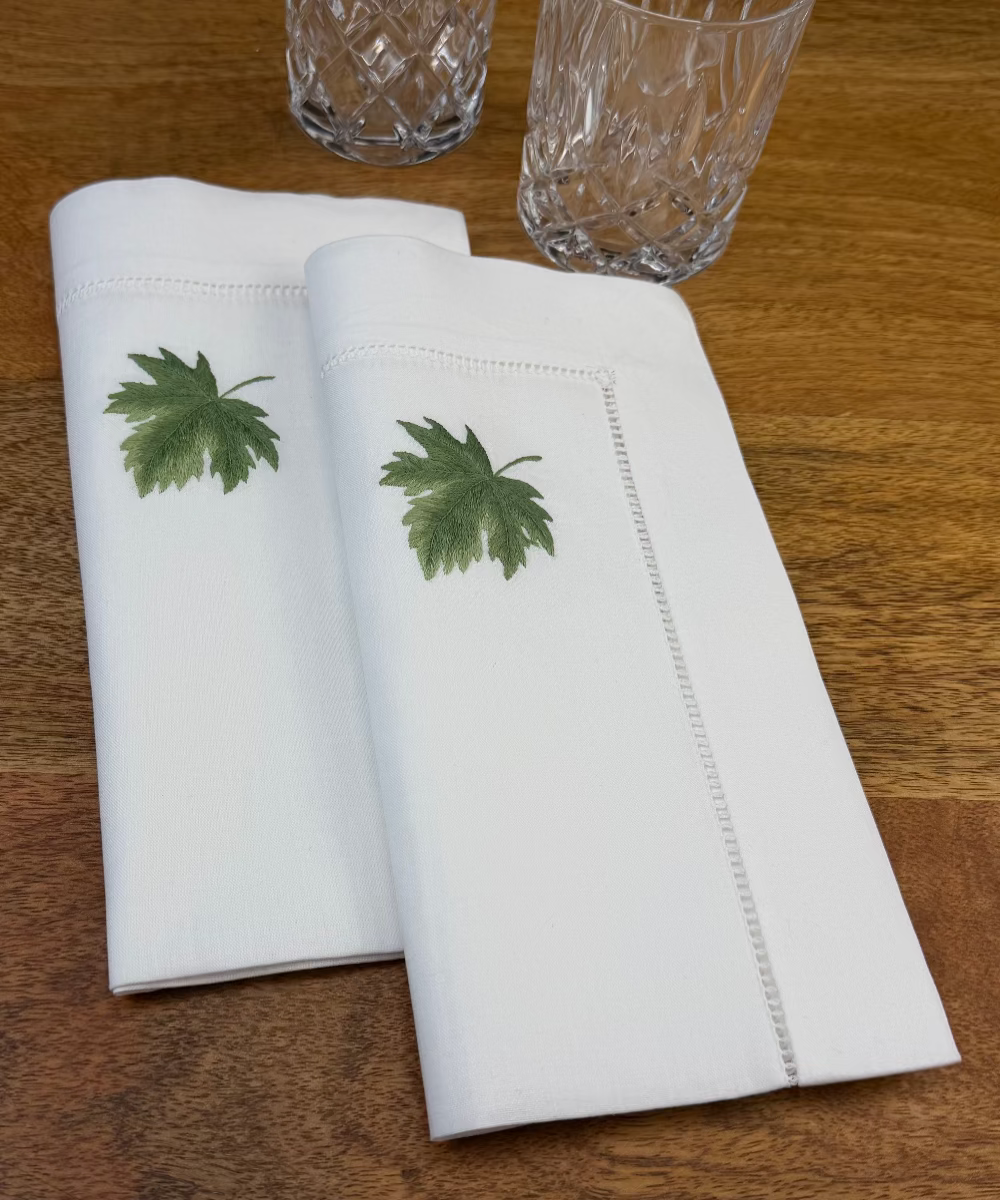 Stoffservietten Ahorn 50x50cm handbestickt und mit Gläsern auf Holztisch dekoriert.