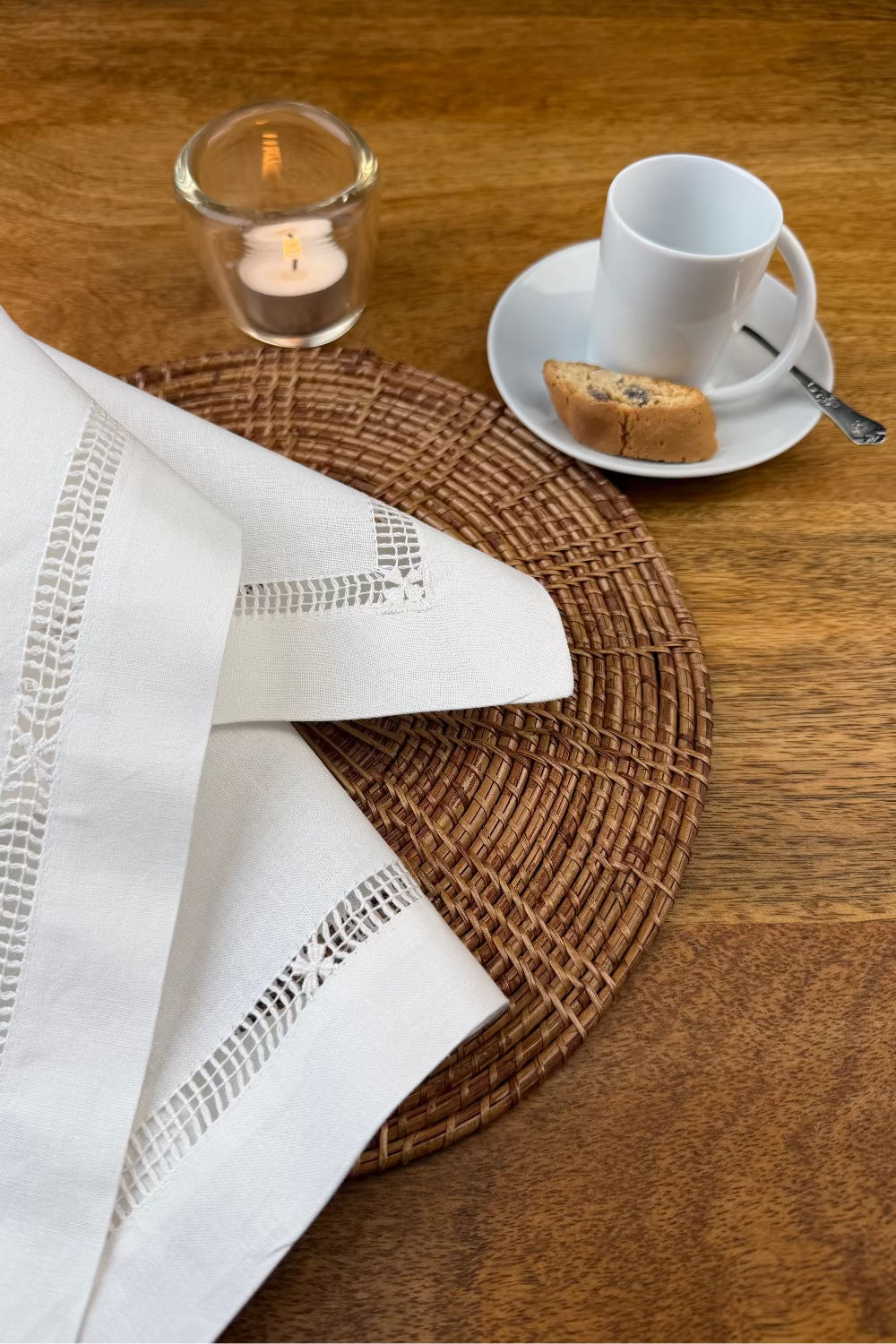 Stoffserviette weiß Fiorenze Hohlsaum mit  Kaffeetasse und Teelicht dekoriert.