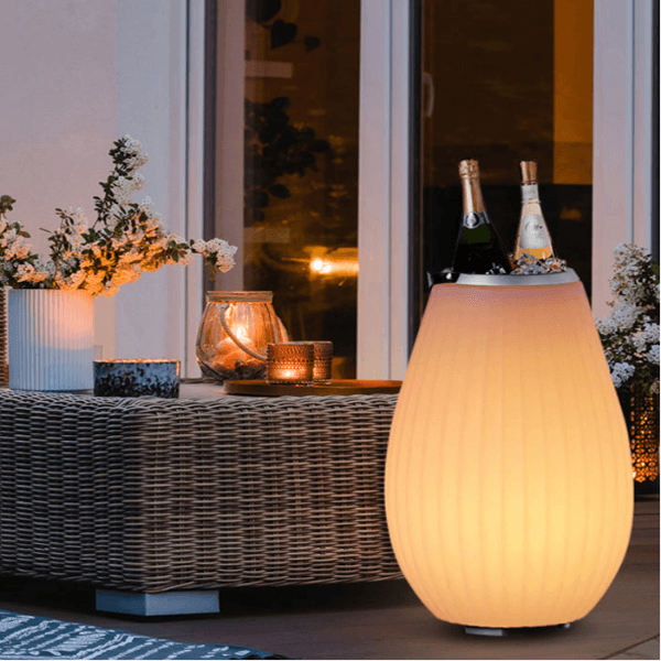 The Joouly  in gelbem Licht auf Gartenterrasse als Sektkühler und Lautsprecher verwendet