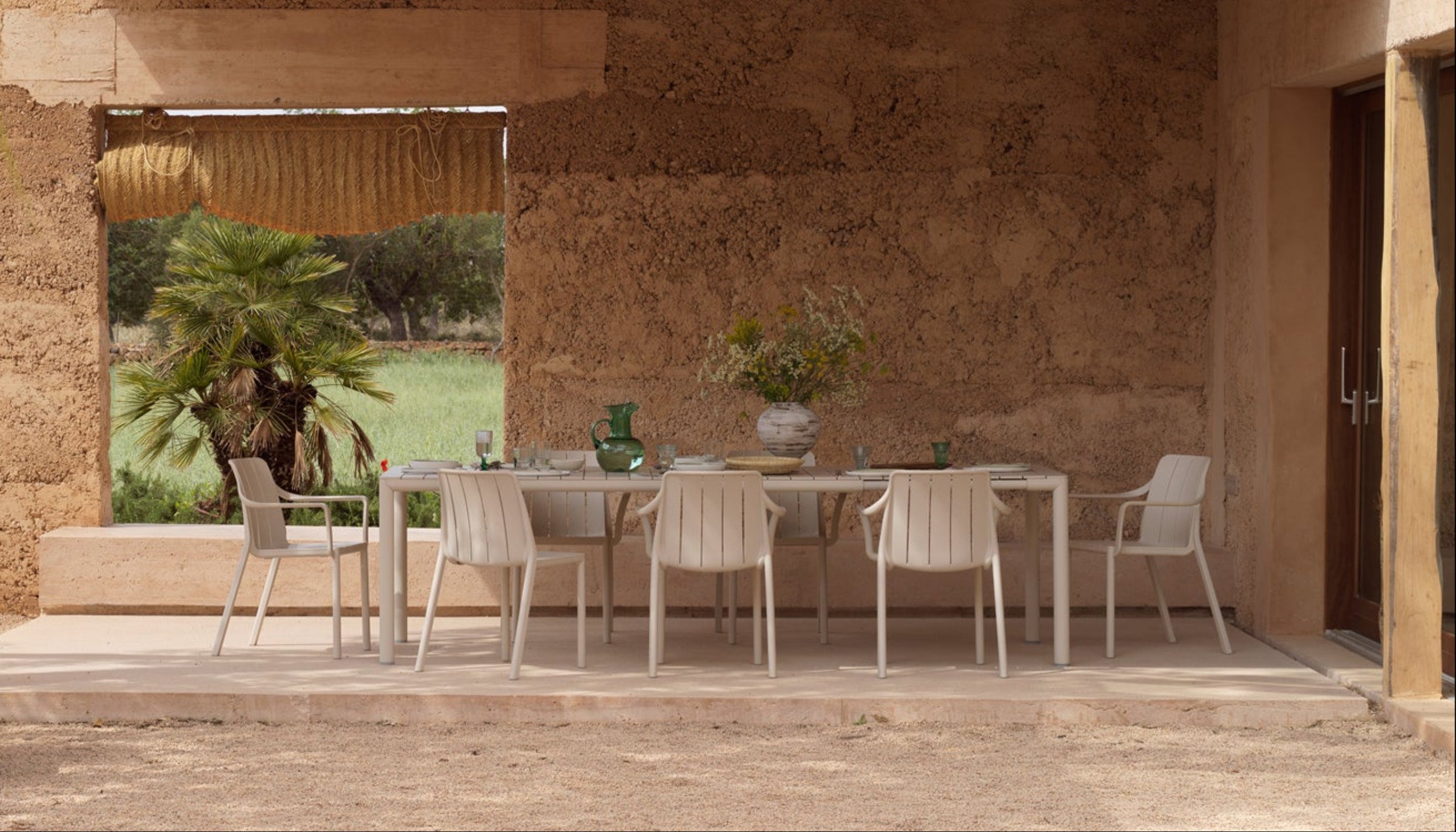 Tevere Outdoor Tisch mit Tberina Outdoor Stühlen in der Farbe Corda in einem Meditteranen, teilweise überdachten Innenhof.