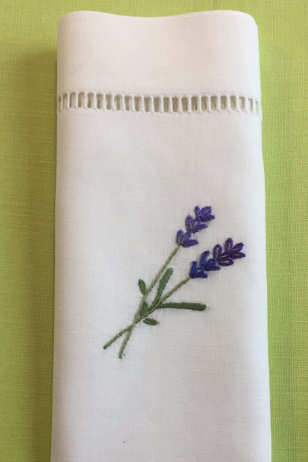 handgestickte Lavendel Zweige auf einer weißen Serviette aus Halbleinen mit Hohlsaum