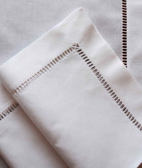 Weiße Leinenserviette aus feingewebtem Leinen mit handgesticktem Gitterhohlsaum.