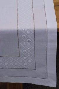 Tischläufer aus feingewebter weißer Baumwolle mit aufgestickten weißen Blüten und Gittern in Schattenstickerei