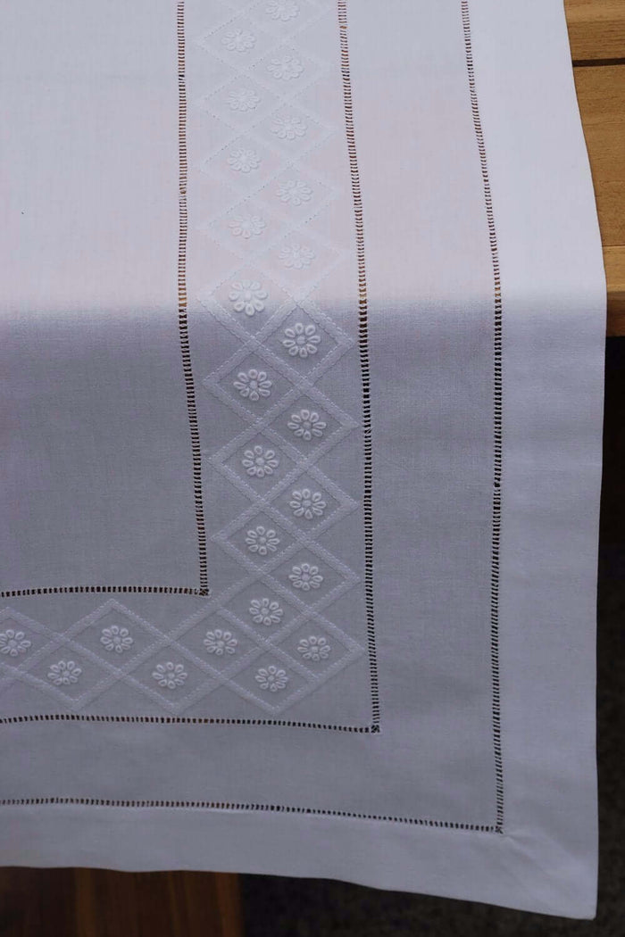 Tischläufer aus feingewebter weißer Baumwolle mit aufgestickten weißen Blüten und Gittern in Schattenstickerei