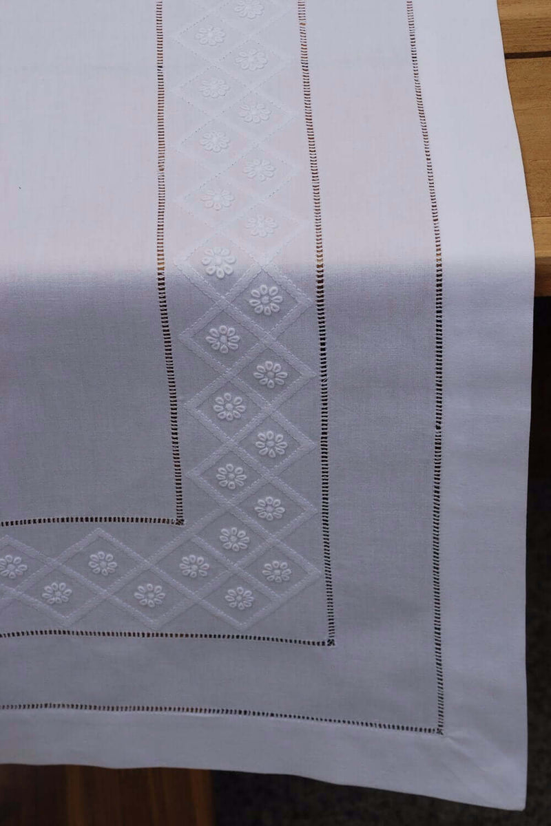 Tischläufer aus feingewebter weißer Baumwolle mit aufgestickten weißen Blüten und Gittern in Schattenstickerei